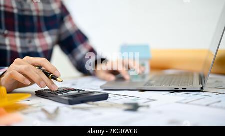 close-up image, Professional Asian female architect or engineer using scientific calculator and laptop computer, working in her office. Stock Photo