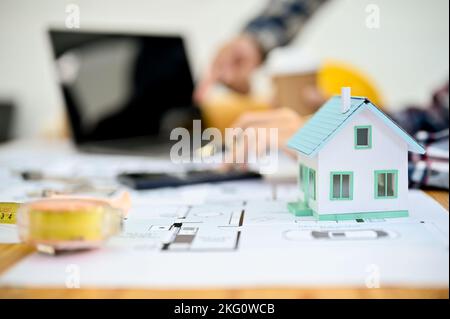 Engineer or architect desk workspace with house model, measuring tape, blueprint and calculator. close-up image Stock Photo