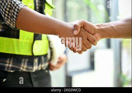 close-up and cropped image, Professional and successful construction engineer shaking hands with his coworker. Stock Photo