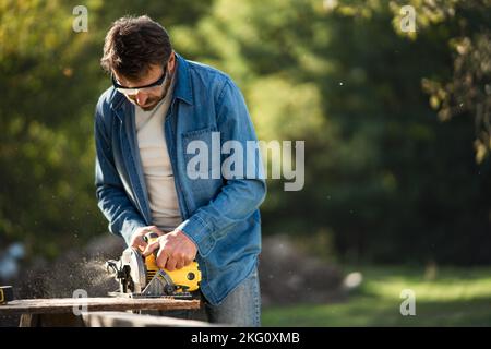 Craftsman working with circular saw at construction site Stock Photo