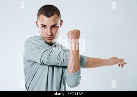 I will not be stopped. Portrait of a handsome young man stretching his arms against a gray background. Stock Photo