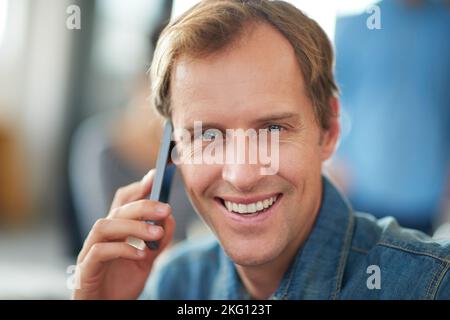 Making important business connections. a man sitting in an office talking on a cellphone with colleagues in the background. Stock Photo