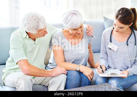 My prescription is as follows...A doctor explaining medical care to a senior patient and his spouse. Stock Photo