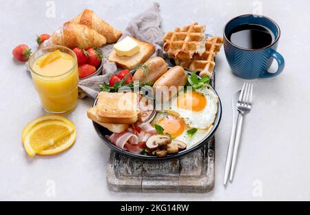 Full English breakfast with fried egg, sausage, bacon and toast on grey background. Stock Photo
