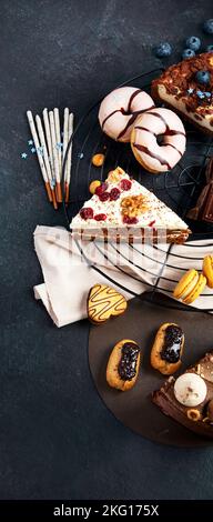 Table with various cookies, donuts, cakes, cheesecakes on dark background.  Delicious dessert table. Top view, flat lay Stock Photo