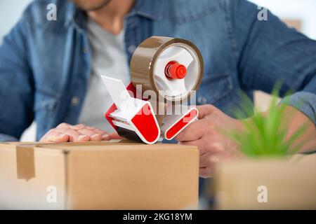 close view of man using a parcel tape dispenser Stock Photo