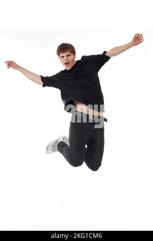 young man in black t-shirt smiling jumping high Stock Photo