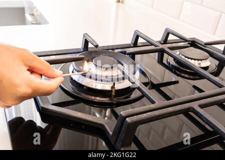 Hand turns on the gas burner on the gas stove Stock Photo