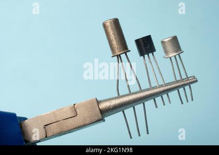 Precision pliers grips three different types of transistors Stock Photo