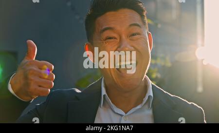 Portrait happy smiling toothy satisfied successful glad Asian 40s middle-aged man boss leader businessman standing outdoors in sun lights in sunbeams Stock Photo