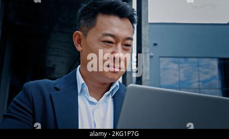 Happy smiling positive Korean Chinese 40s middle-aged businessman lawyer freelancer investor employer entrepreneur smile success with online project Stock Photo