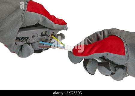 An electrician removes insulation from a three-core copper wire with a stripper Stock Photo