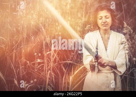 Beautiful woman in nature with a sword in her hand. Stock Photo