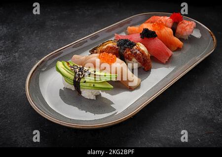 Assorted Nigiri sushi on a plate, on dark concrete. Top view Stock Photo