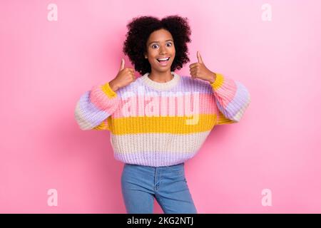 Photo of excited impressed ecstatic girl with perming coiffure dressed knit sweater showing thumbs up isolated on pink color background Stock Photo