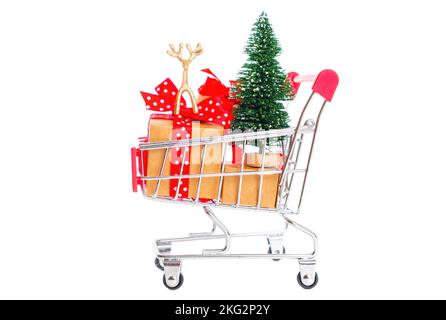 Toy christmas props and wrapped gift boxes in a miniature shopping trolley isolated on white. Getting ready for the new year's eve. Stock Photo