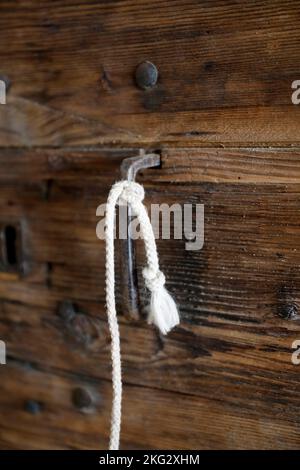 Old wooden door with a white rope. Close up.  France. Stock Photo