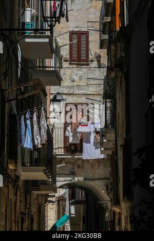 Woman drying laundry on her balcony in Bitonto, Puglia, Italy. Stock Photo