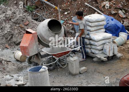 Worker at construction site.  Cement mixing machine. Vietnam. Stock Photo