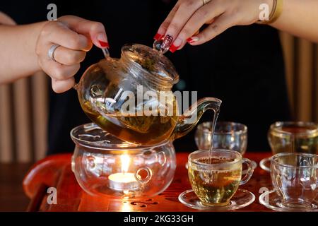 Woman delicately pouring tea from a glass style teapot Japanese tea ceremony.  Vietnam. Stock Photo
