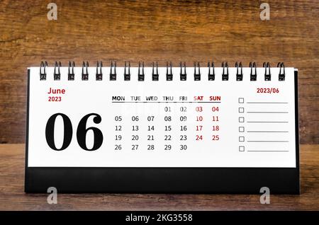 June 2023 Monthly desk calendar for 2023 year on wooden background.