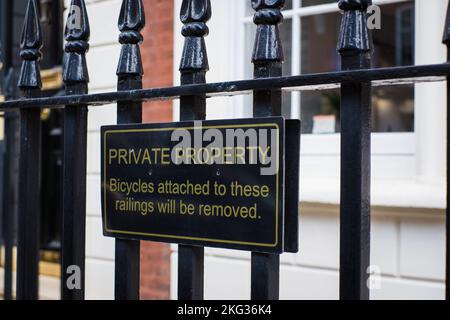 Black metal warning sign on public fence 'Private property - Bicycles attached to these railings will be removed.' Stock Photo