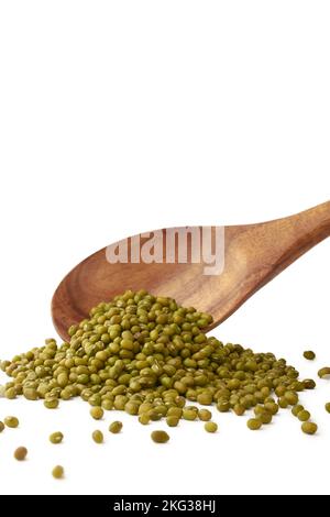 raw green gram or mung beans, high nutrients and antioxidant grain legumes falling from a wooden spoon, isolated on white background, selective focus Stock Photo