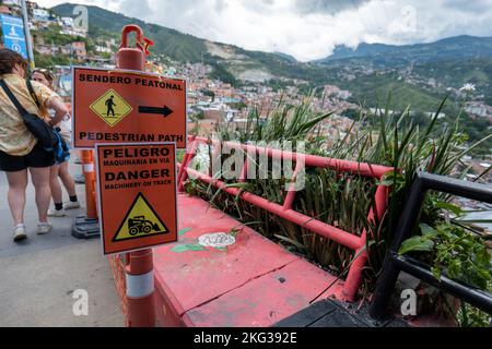 Medellin, Antioquia, Colombia - September 13 2022: Signs That Read 'PEDESTRIAN PATH, DANGER, MACHINERY-ON ROAD, MACHINERY ON TRACK' in Comuna 13 Touri Stock Photo