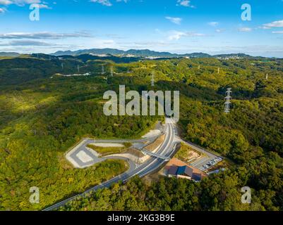 Empty road curving through green rolling hills and high voltage towers Stock Photo