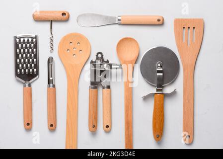 Set of different stainless steel kitchen utensils on concrette stucco background top view. Can opener, corkscrew, pizza cutter, grater, potato peeler, Stock Photo