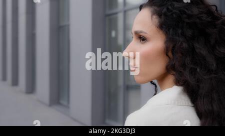 Close up back view Caucasian pensive thoughtful brunette lady with long curly hair looking away thinking dreaming pondering think waiting standing Stock Photo