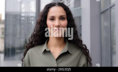 Close-up female portrait outdoors in city multiracial multiethnic Caucasian Latina Hispanic beautiful businessperson elegant 30s smiling woman looking Stock Photo