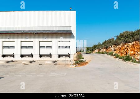 Facade shot of newly constructed logistic warehouse featuring empty loading docks in the Var, France Stock Photo