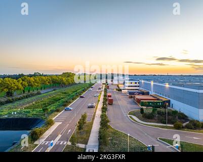 Drone shot of industrial outer area featuring trucks parked in loading row and cars parking on the other side in the Val d'Oise, France Stock Photo