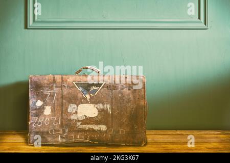 Retro styled image of a weathered vintage travel suitcase in an old living room Stock Photo