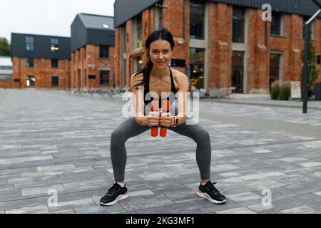 Fitness woman doing squat exercises with dumbbells Stock Photo