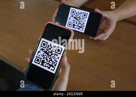 Women's hand uses a mobile phone application to scan QR codes in stores that accept digital payments without money on the table. QR code payment and c Stock Photo