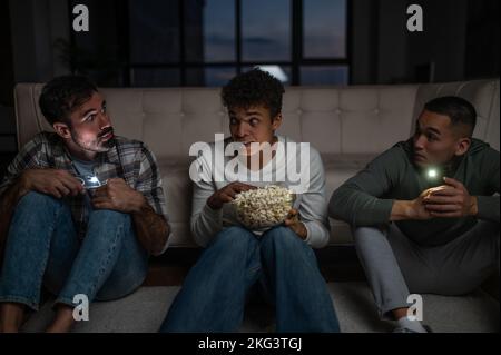 Company of three friends seated in the darkness Stock Photo