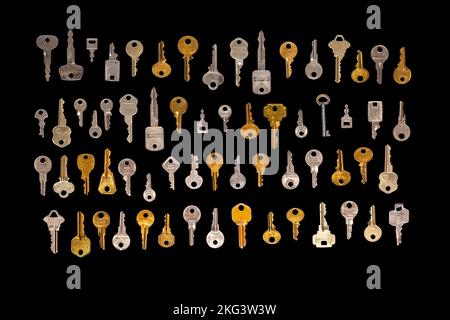 Top aerial view of a group of many different keys isolated on a black background. Stock Photo