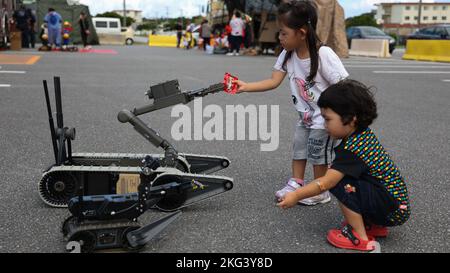 A First Look 110 and a Small Unmanned Ground Vehicle 310, tactical mobile robots remotely controlled by explosive ordnance disposal technicians, hand local Okinawan preschool students candy during a Halloween Carnival event on Camp Hansen, Okinawa, Japan, Oct. 28, 2022. Camp Hansen hosted a Halloween Carnival event for over 300 Okinawan students to experience American holiday traditions. Camp Hansen has hosted this event for more than 10 years, helping to develop and deepen international relations. Camp Hansen,Halloween,III MEF,USMC,USO, Stock Photo