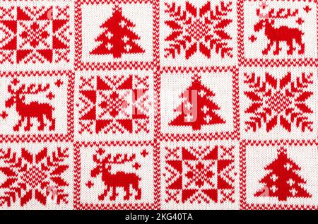 Red knitted fabric with white moose, fir tree and snowflake Scandinavian style geometric ornament cristmas background Stock Photo