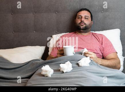 Middle-aged man in bed sick with flu symptoms Stock Photo