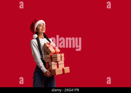 Beautiful Arab Woman In Santa Hat Holding Stack Of Gift Boxes Stock Photo