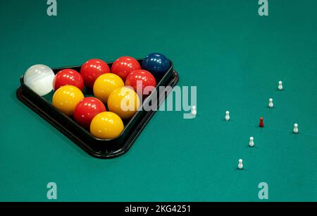 From above triangle rack with balls placed near skittles arranged in cross on green billiards table Stock Photo