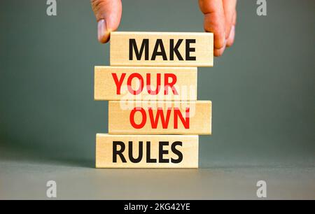 Make your own rules symbol. Concept words Make your own rules on wooden cubes. Beautiful grey table grey background. Businessman hand. Business motiva Stock Photo