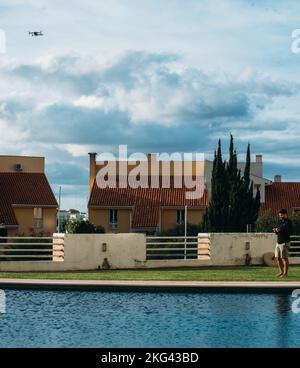 Young man operating an unmanned aircraft vehicle also known as a drone next to a residential pool Stock Photo