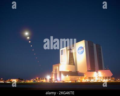 A composite of ten images shows the Moon’s progression during a total lunar eclipse above NASA’s Vehicle Assembly Building on Nov. 8, 2022. Mars is visible trailing the Moon. Stock Photo