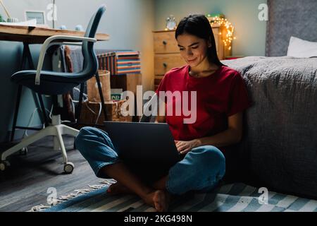Young hispanic woman working with laptop while sitting on floor at home Stock Photo