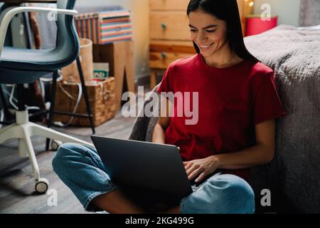 Young hispanic woman working with laptop while sitting on floor at home Stock Photo
