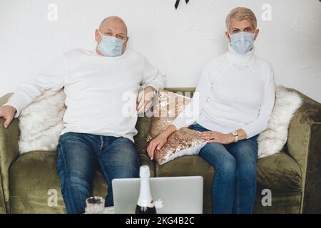 Senior man and woman wearing protective masks and resting in their house Stock Photo